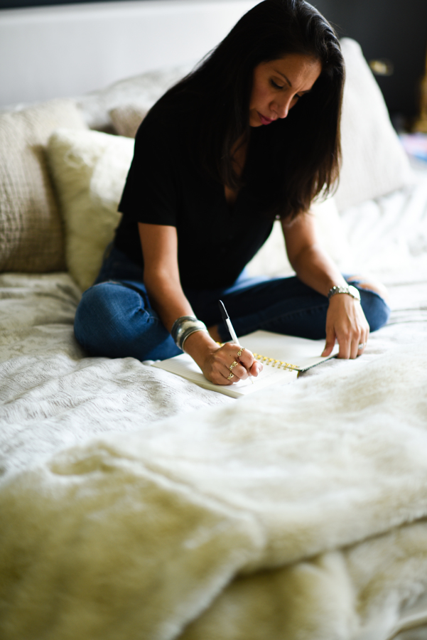 woman writing in journal on bed